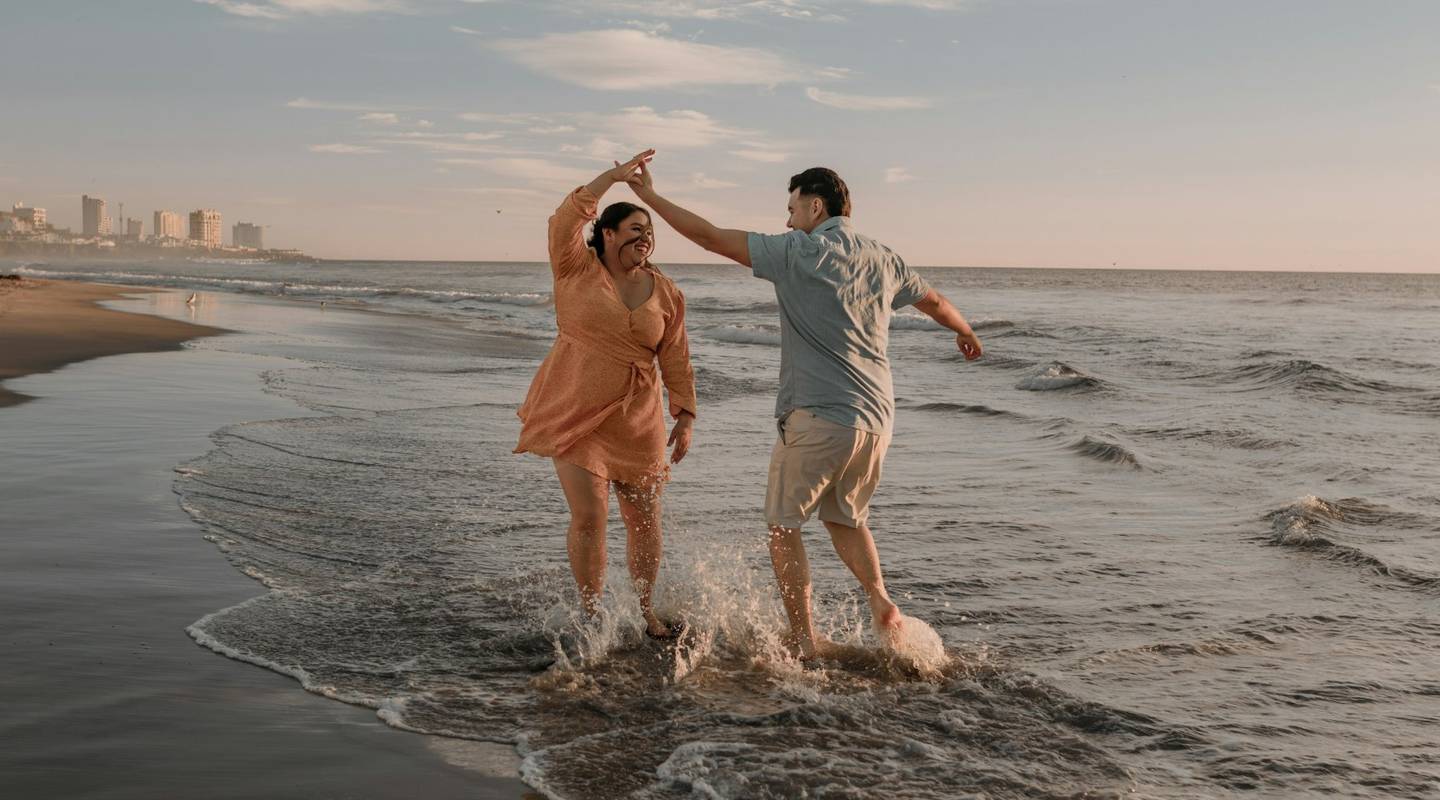Erfahrungen mit schlauer.reisen Paar läuft lachend durch flaches Meerwasser am Strand