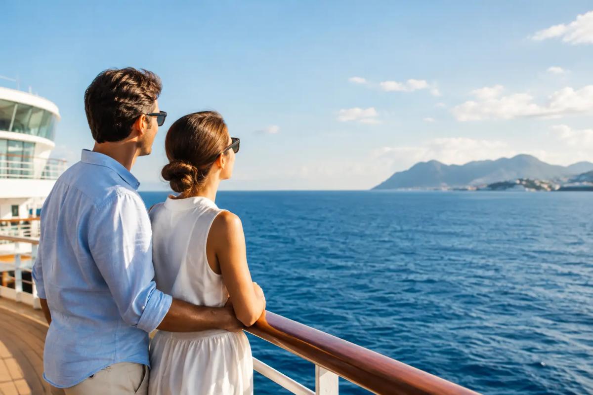 Luxuskreuzfahrten vergleichen: die wichtigsten Kriterien Paar an Deck eines Kreuzfahrtschiffs mit Blick auf die Küste