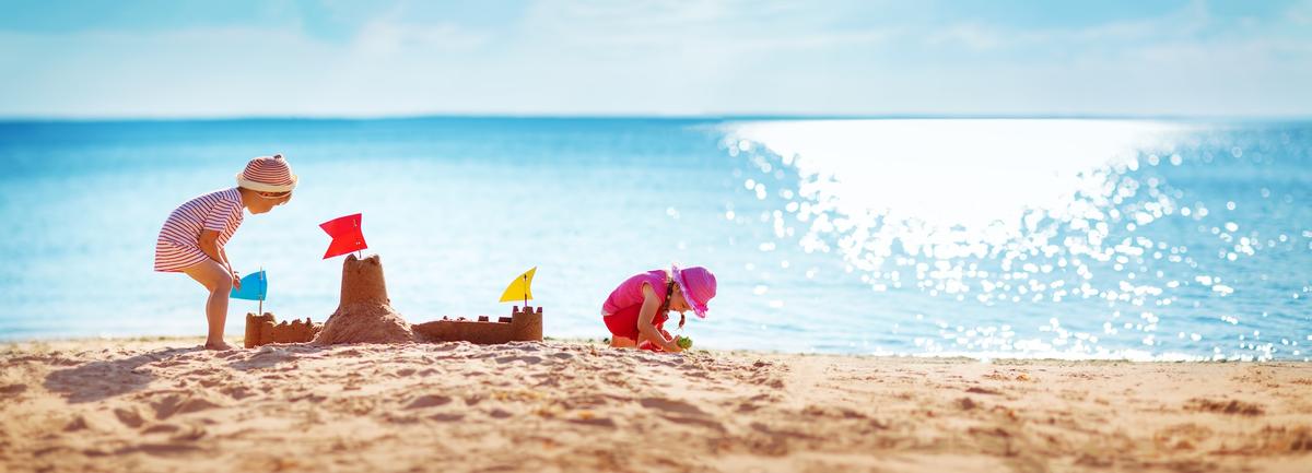 Kind baut Sandburg am Strand auf den Kanaren