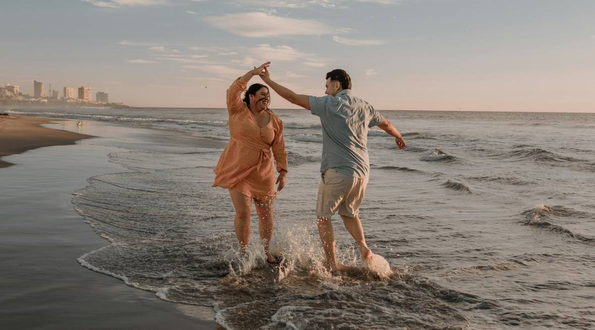 Erfahrungen mit schlauer.reisen Paar läuft lachend durch flaches Meerwasser am Strand