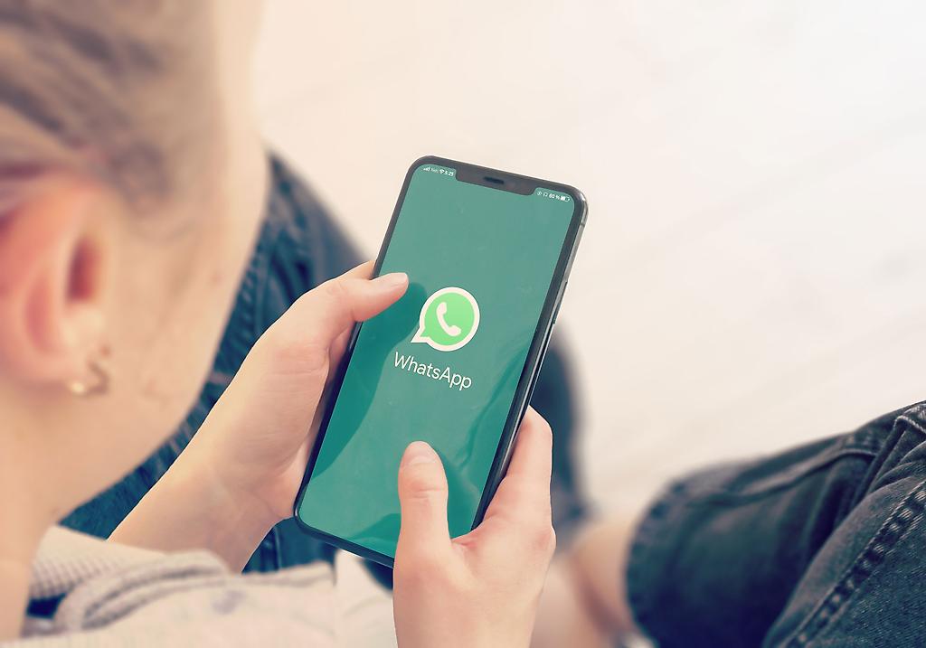 Frau hält Smartphone in der Hand WhatsApp ist geöffnet