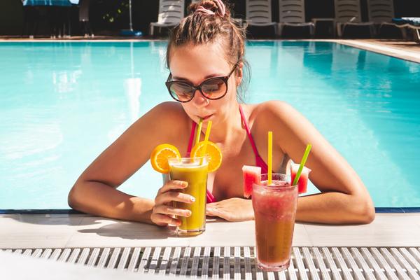 Frau mit 2 tropischen Getränken im all inclusive Urlaub